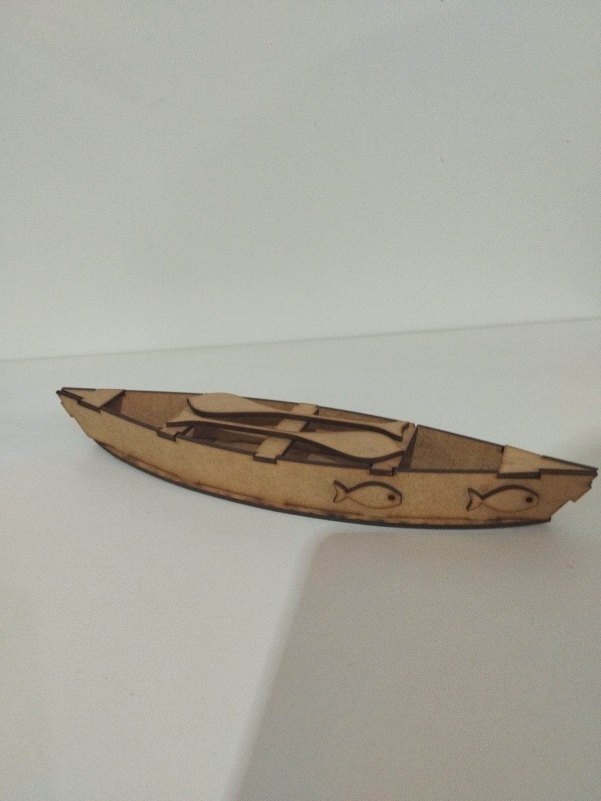 Canoa decorativa de MDF cru com dois peixes recortados na lateral e remos no interior