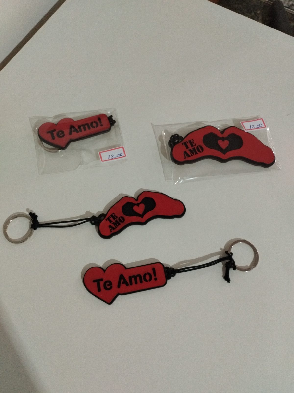 Quatro chaveiros de madeira vermelhos com a frase Te amo e desenho de mãos em formato de coração