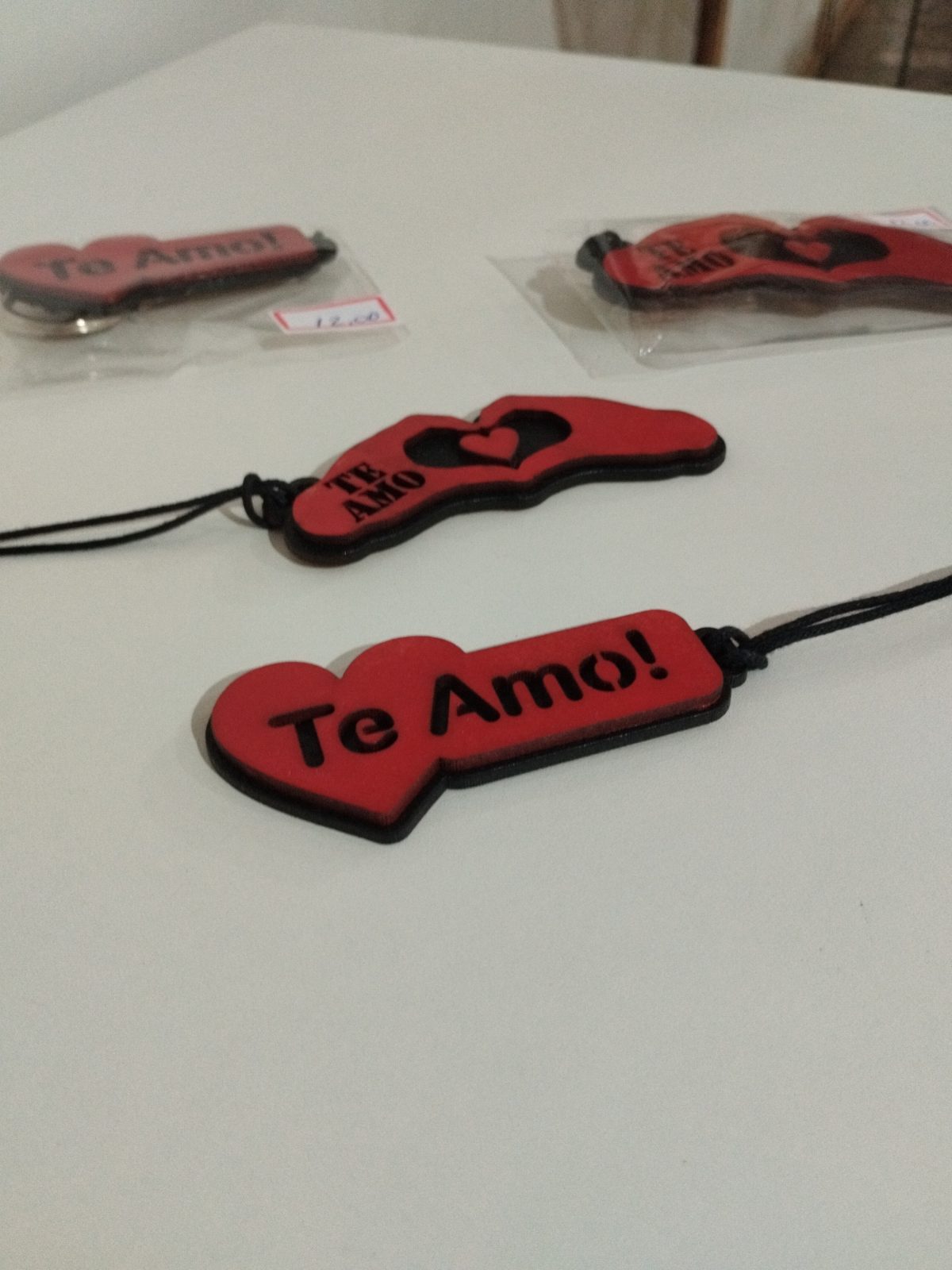 Chaveiros de madeira pintada vermelha vistos em ângulo, com frases de amor e corações