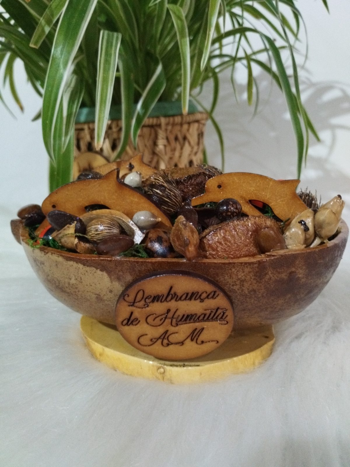 Cuia decorada com sementes e dois golfinhos de madeira, com placa gravada na frente