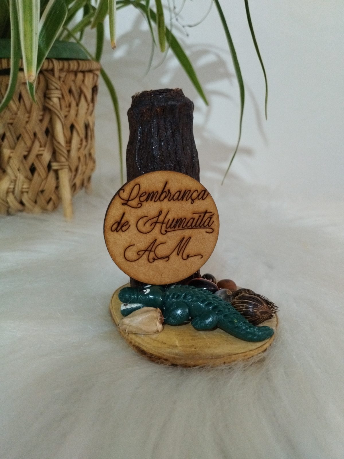 Porta-canetas artesanal com jacaré verde e sementes escuras na base, com placa escrita Lembrança de Humaitá AM