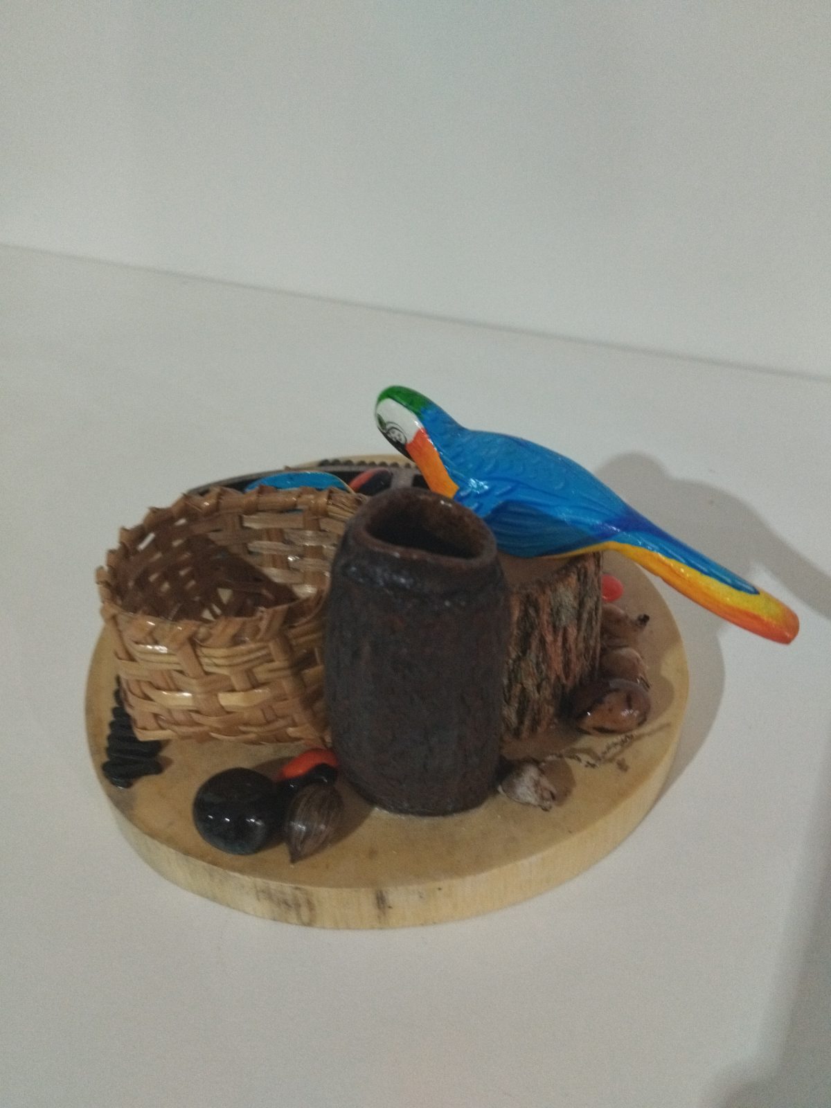 Miniatura regional de Humaitá vista por trás, com arara azul, cesto trançado e recipiente escuro