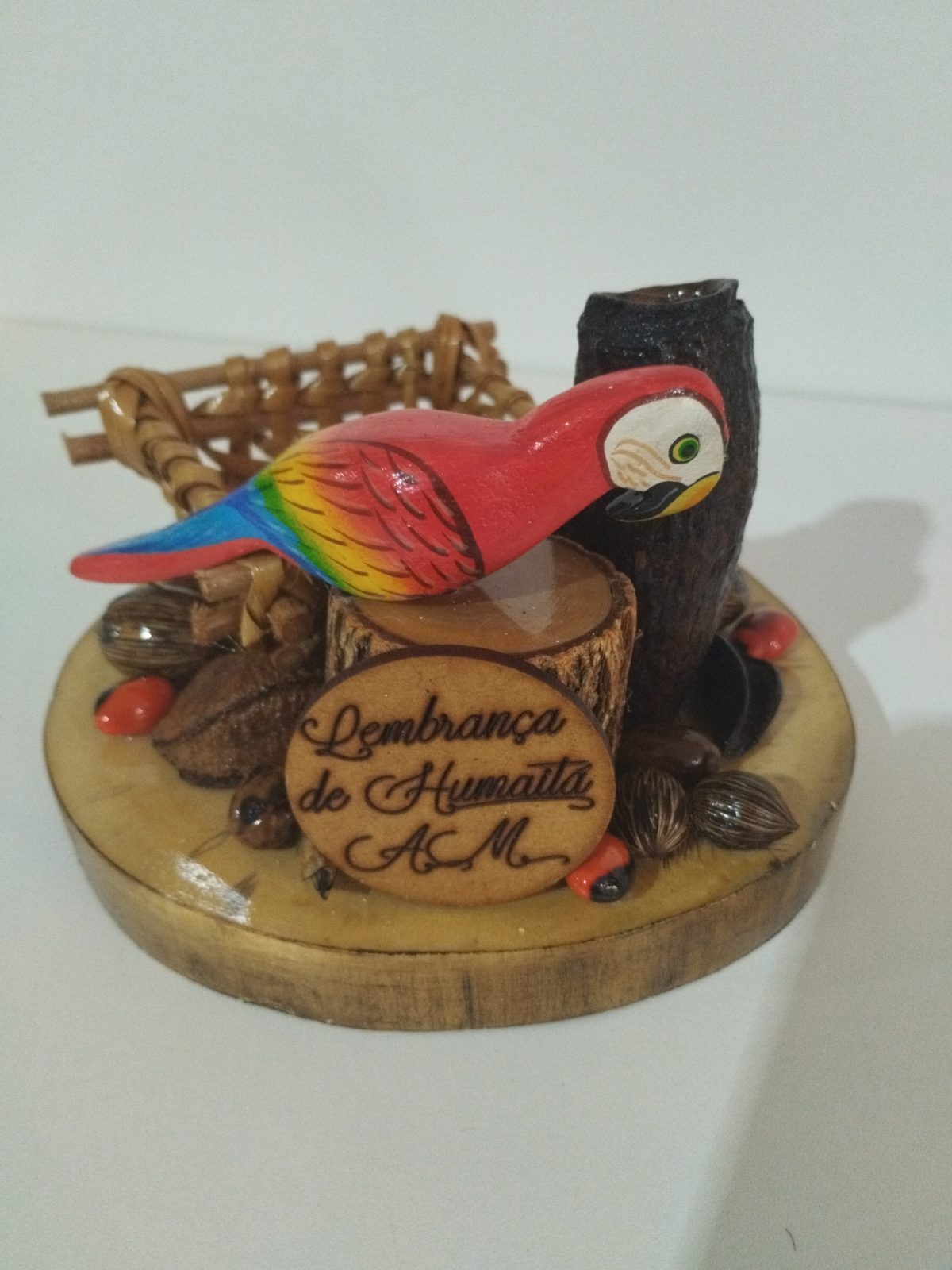 Mimo regional com arara vermelha, placa Lembrança de Humaitá AM e cestinho sobre base circular de madeira