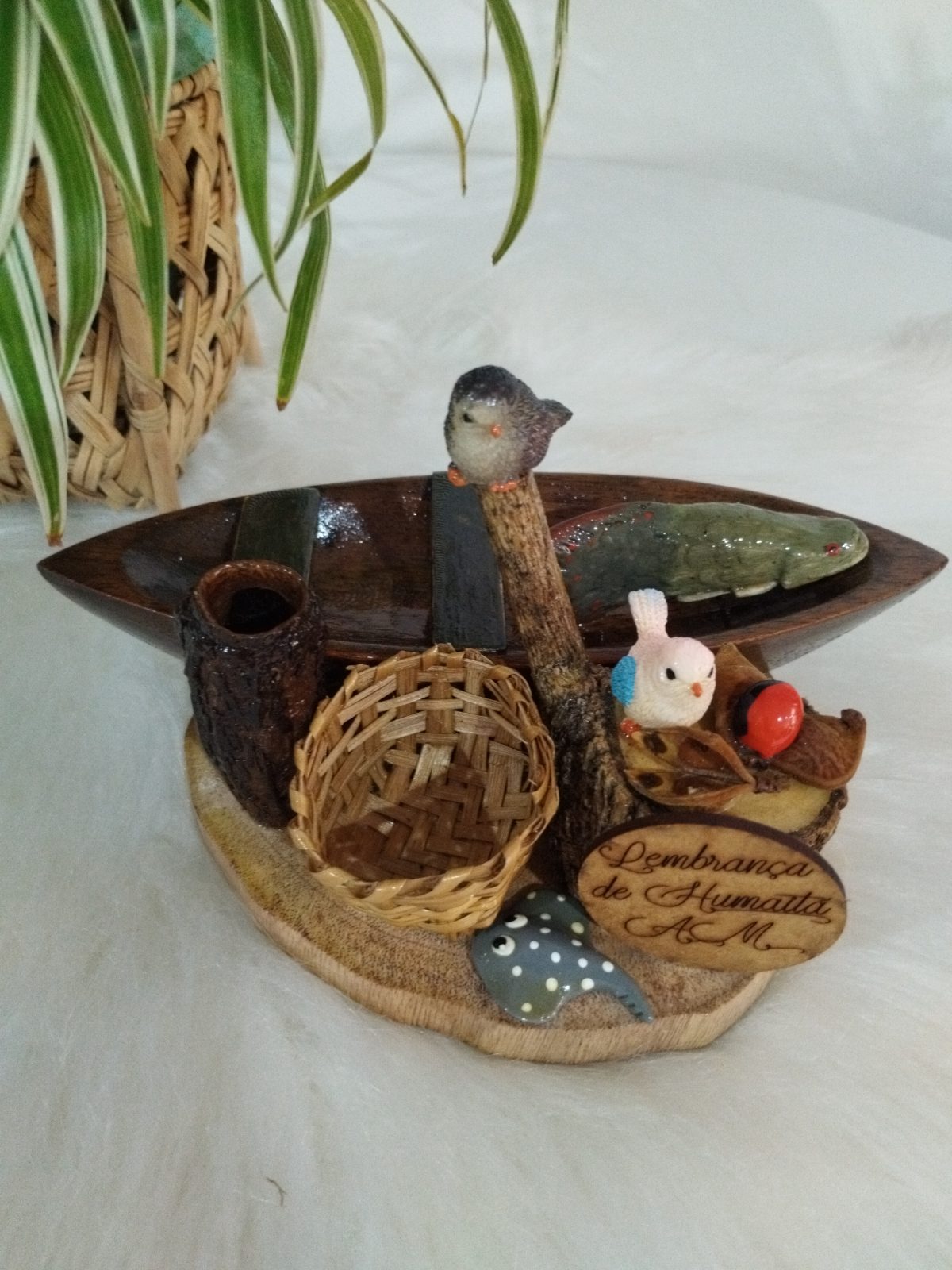 Miniatura de canoa com peixe, pássaros e cesto, vista superior da composição regional em madeira