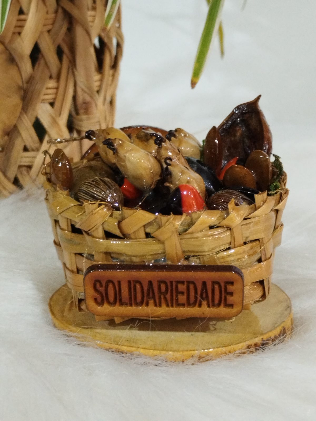 Cestinha de cipó ambé com sementes e placa retangular Solidariedade no verso
