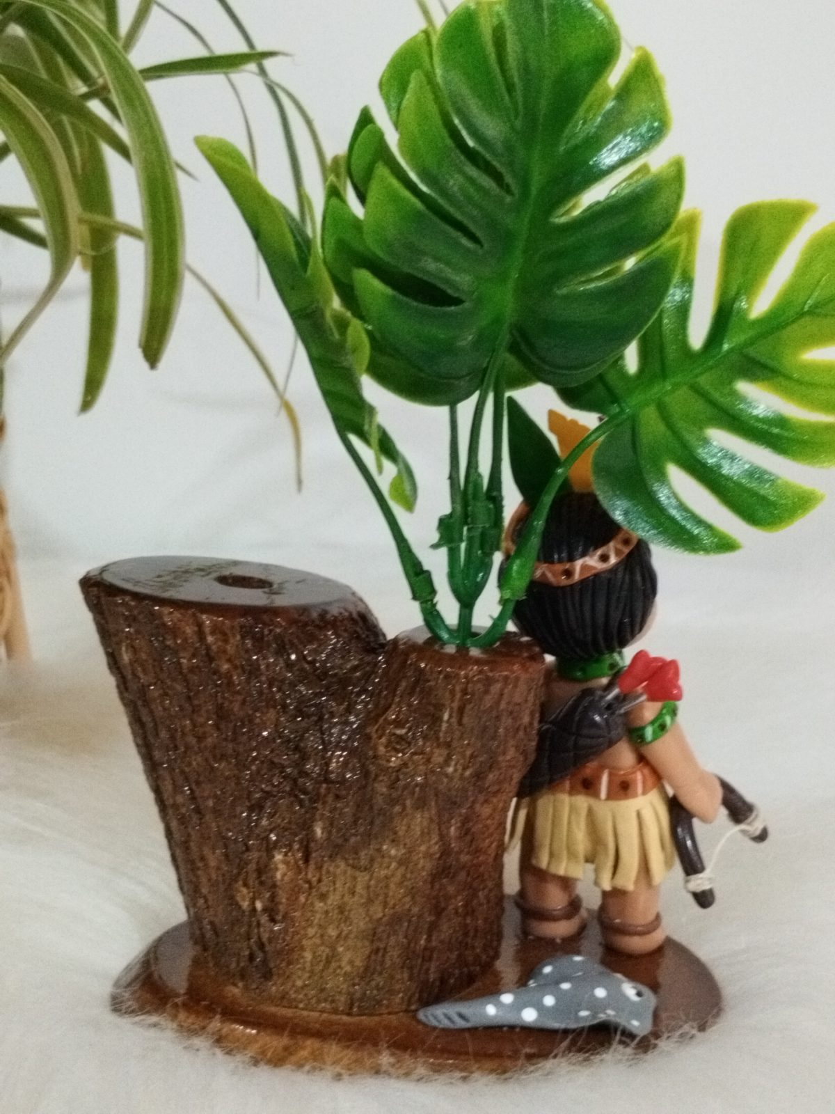 Porta-canetas de madeira com boneco indígena, folhagens e pequeno peixe, visto pelo verso