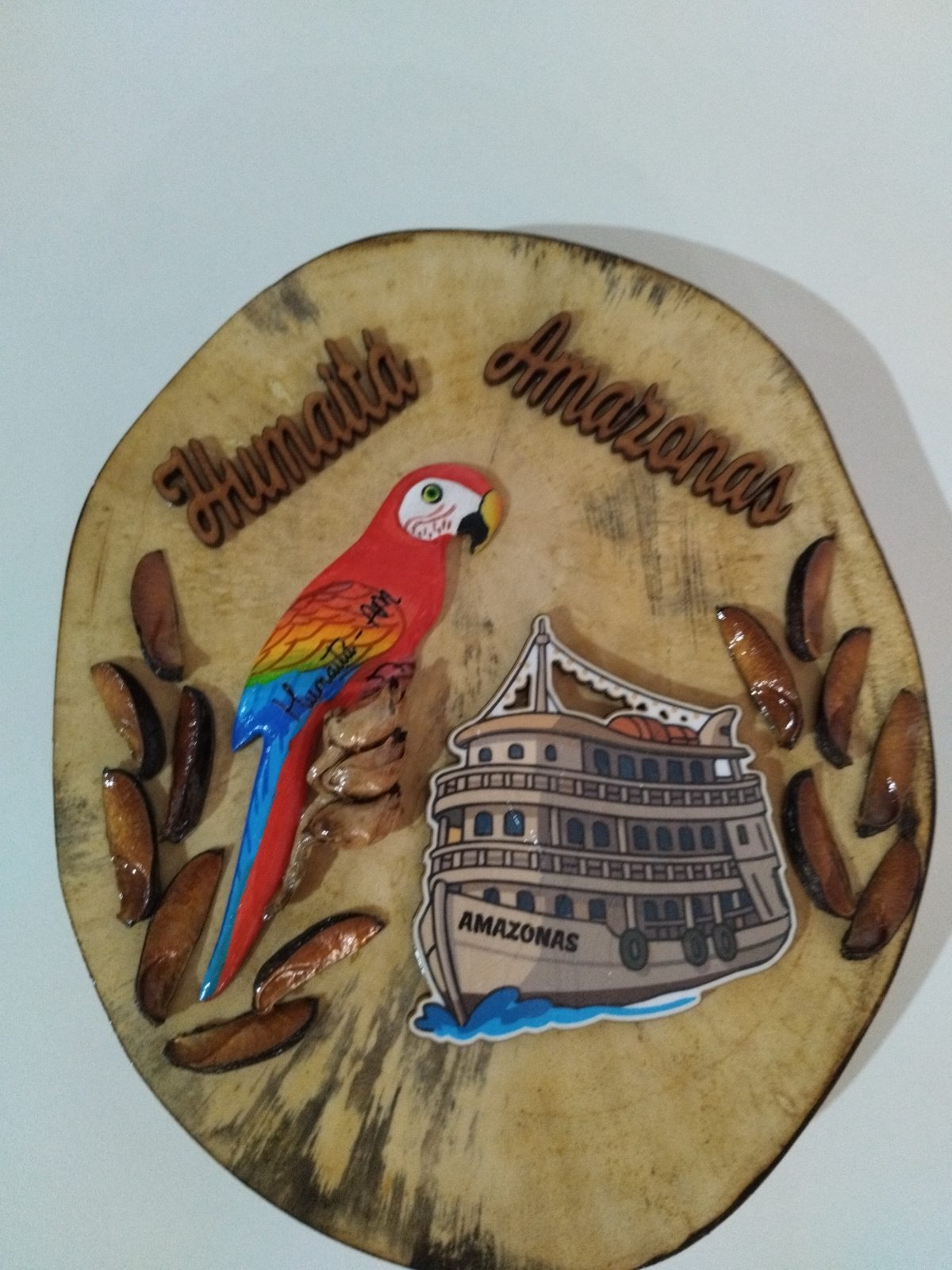 Plaquinha rústica de madeira com arara-vermelha e barco Amazonas, vista frontal aproximada