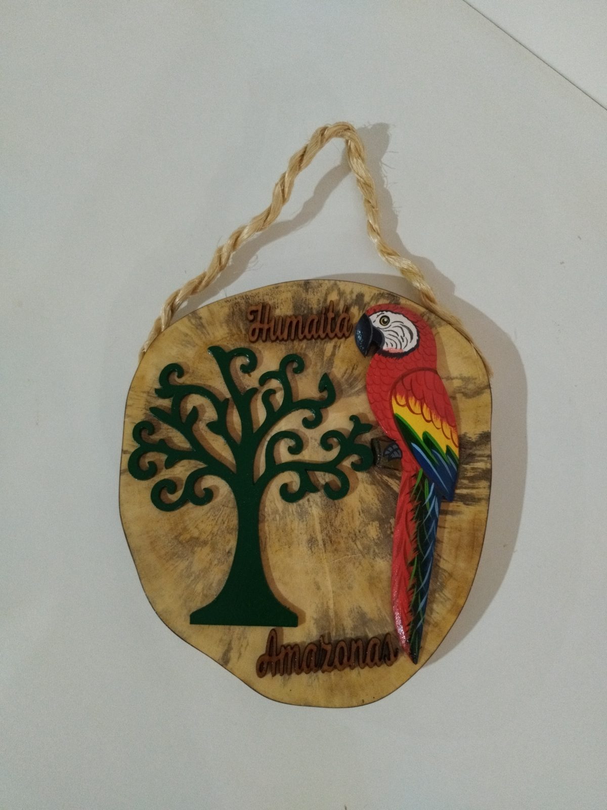 Plaquinha de madeira com árvore verde, arara colorida e as palavras Humaitá e Amazonas