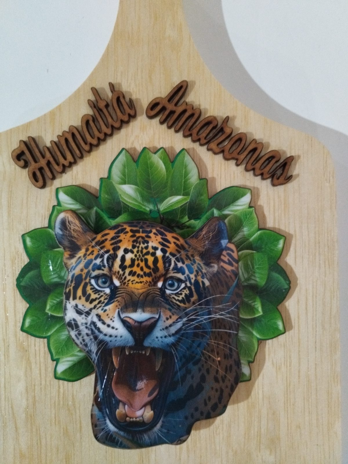 Porta-chaves de madeira em detalhe com cabeça de onça-pintada, folhas e inscrição Humaitá Amazonas