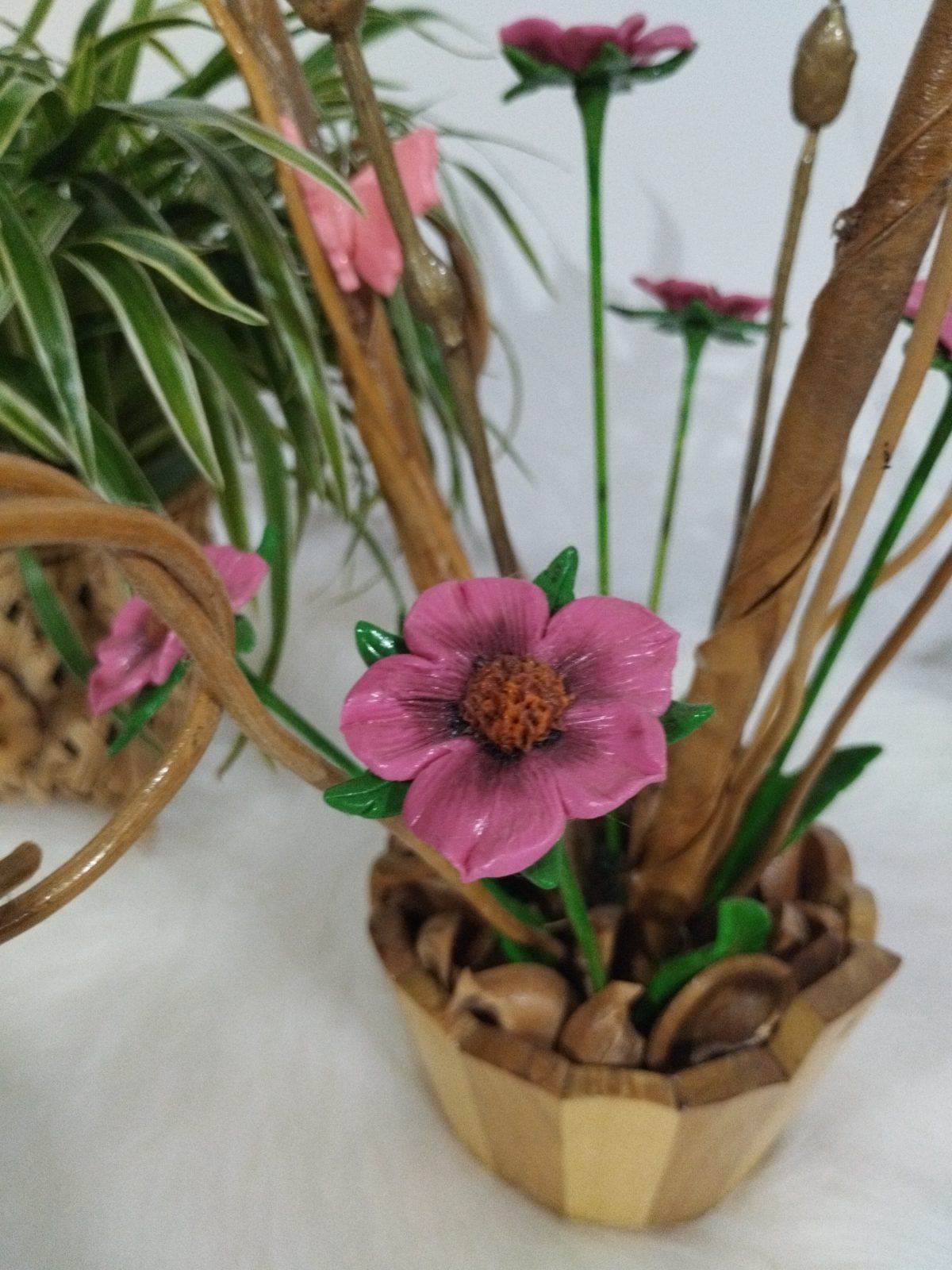 Vaso de madeira com detalhe de flor cor-de-rosa modelada, folhas verdes e sementes marrons