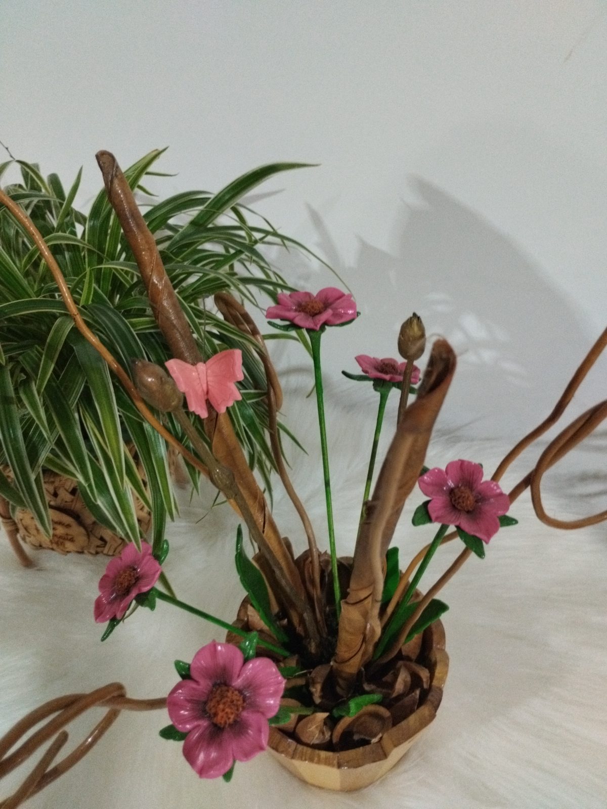 Vaso de madeira com flores cor-de-rosa e borboleta rosa em detalhe