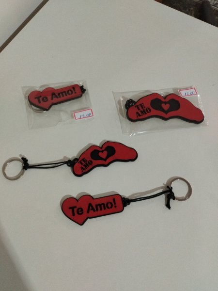 Quatro chaveiros de madeira vermelhos com a frase Te amo e desenho de mãos em formato de coração
