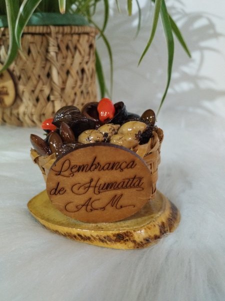 Cestinha de palha com sementes variadas e placa de madeira gravada com a frase Lembrança de Humaitá AM