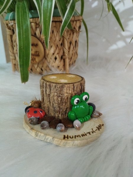 Porta-canetas de madeira com um sapo verde de biscuit e uma joaninha na base.