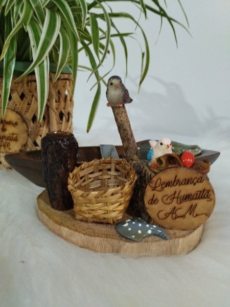 Peça decorativa com base de madeira, canoa, peixe pirarucu, pássaros e mini cesta.