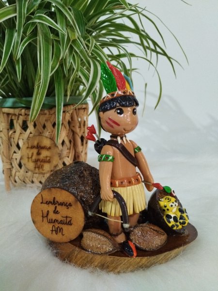 Miniatura de índio com arco e filhote de onça em base de madeira rústica.